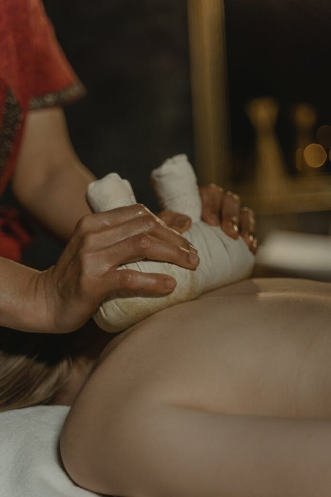 Close-up of a woman receiving a relaxing herbal massage therapy session with selective focus.
